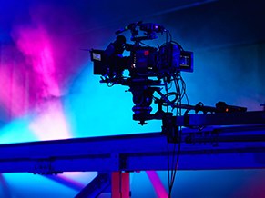 Broadcast camera on a jib arm under blue and pink stage light