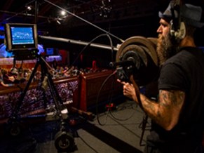 Camera operator in headphones working beside a monitor in the auditorium